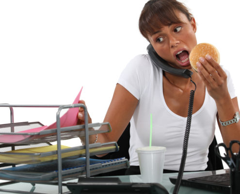 Busy woman eating at her desk